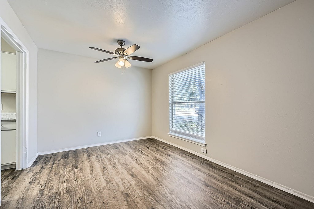 A room with a ceiling fan and a window with blinds.