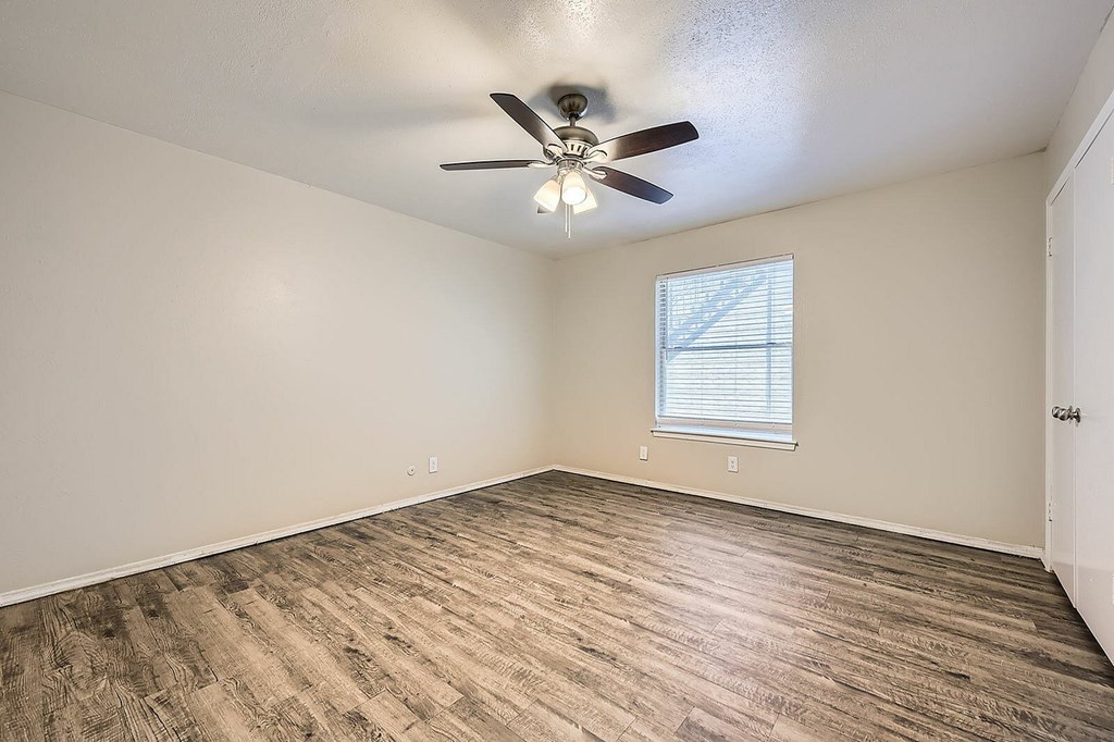 A room with a ceiling fan and a window with blinds.