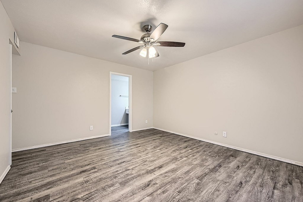 A room with a ceiling fan and wooden flooring.