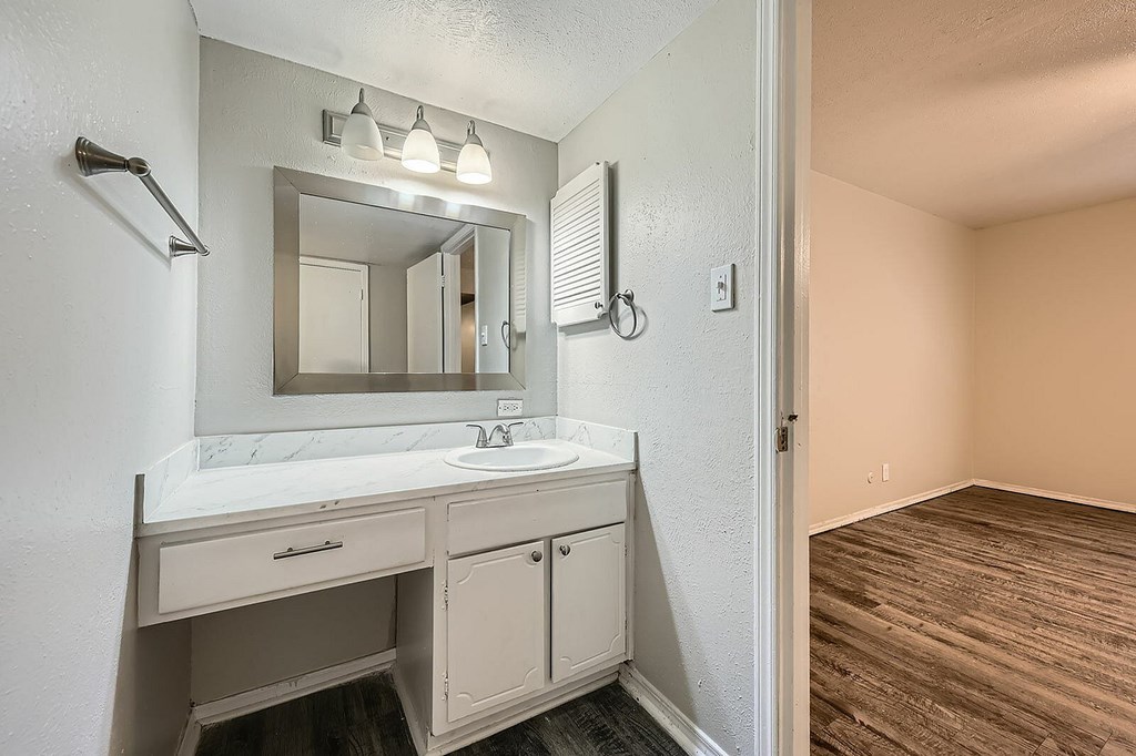 A bathroom with a sink, mirror, and light fixture.