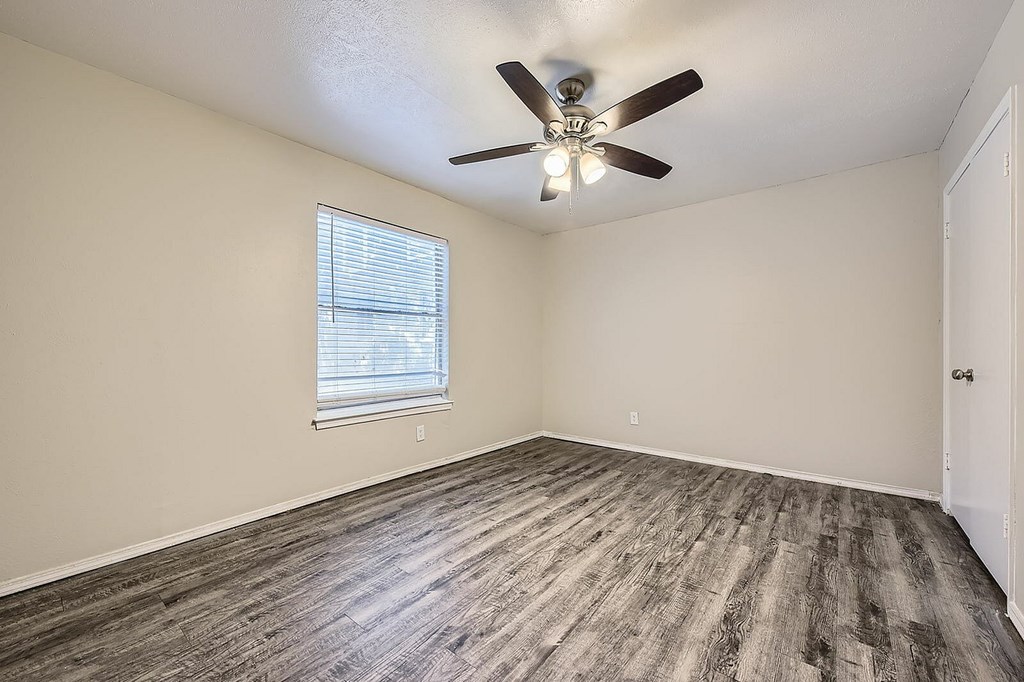 A room with a ceiling fan and a window with blinds.