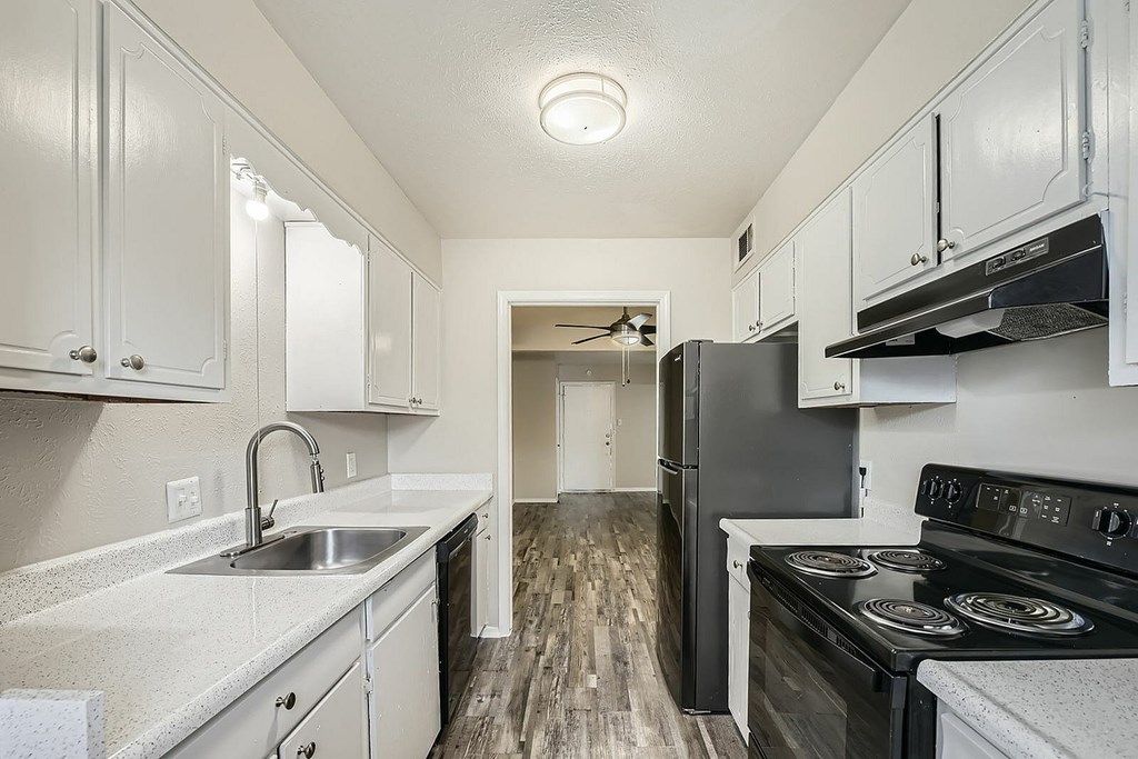A kitchen with black appliances and white cabinets.