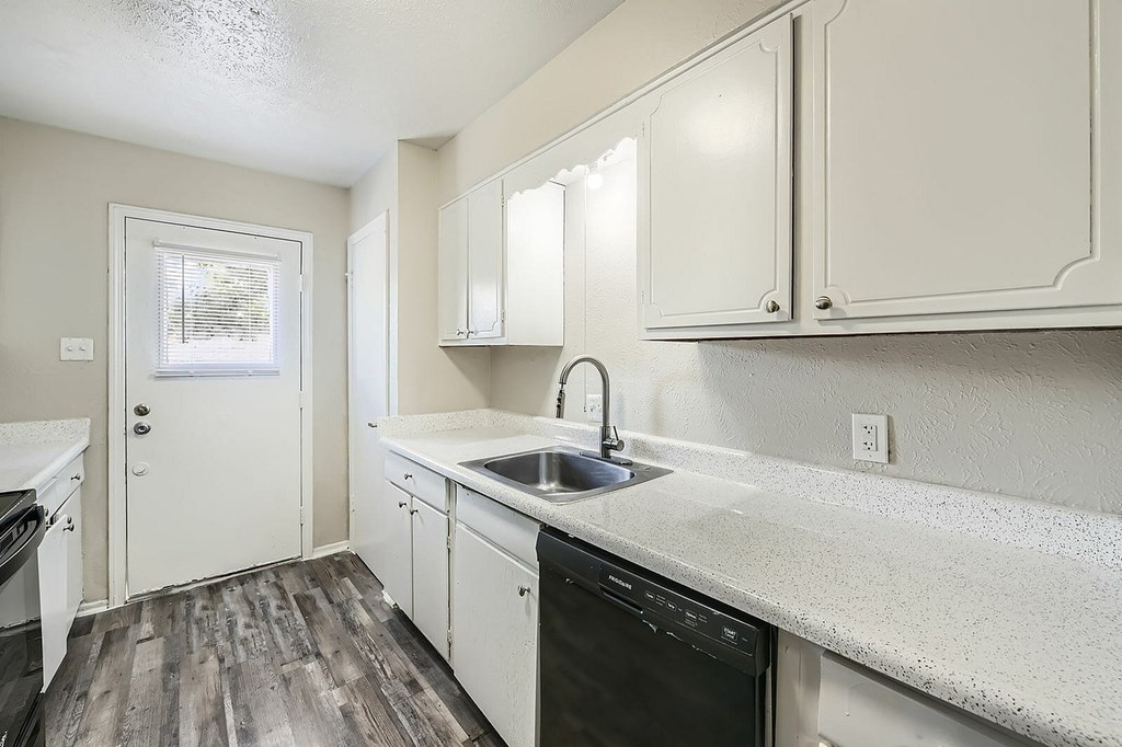 A kitchen with a black dishwasher and white cabinets.