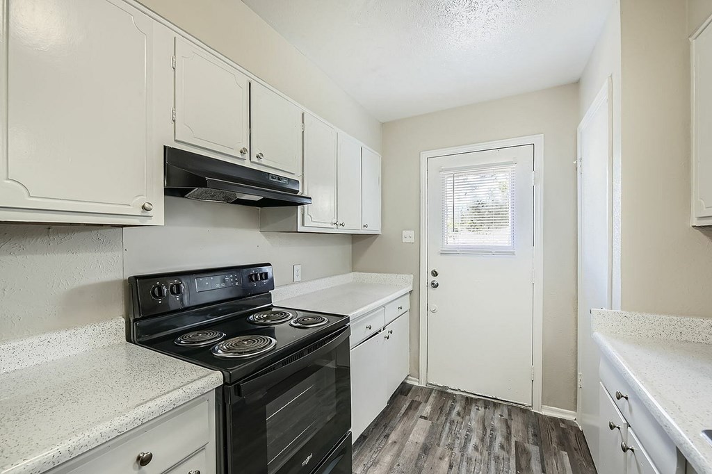 A kitchen with a black stove top oven and white cabinets.