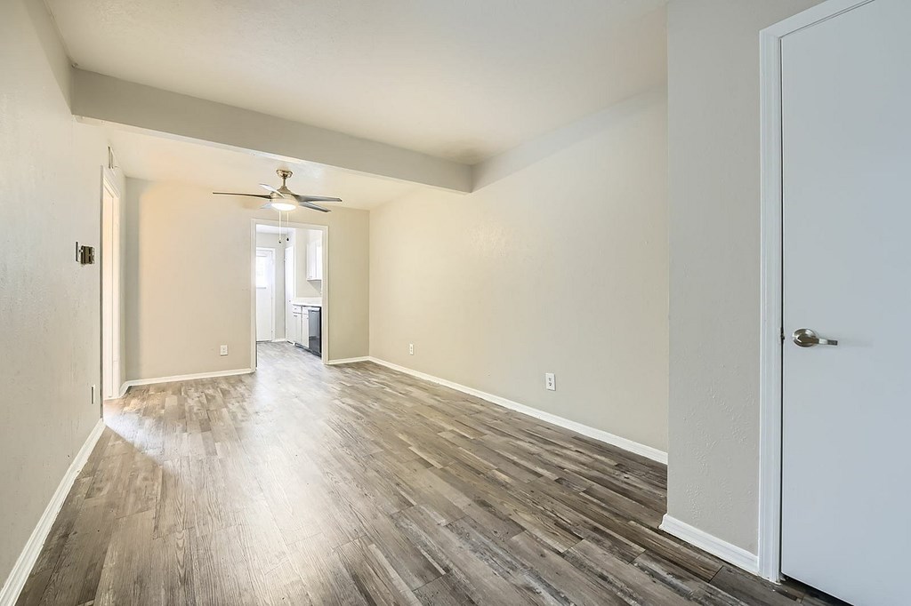 A room with a ceiling fan and wooden flooring.