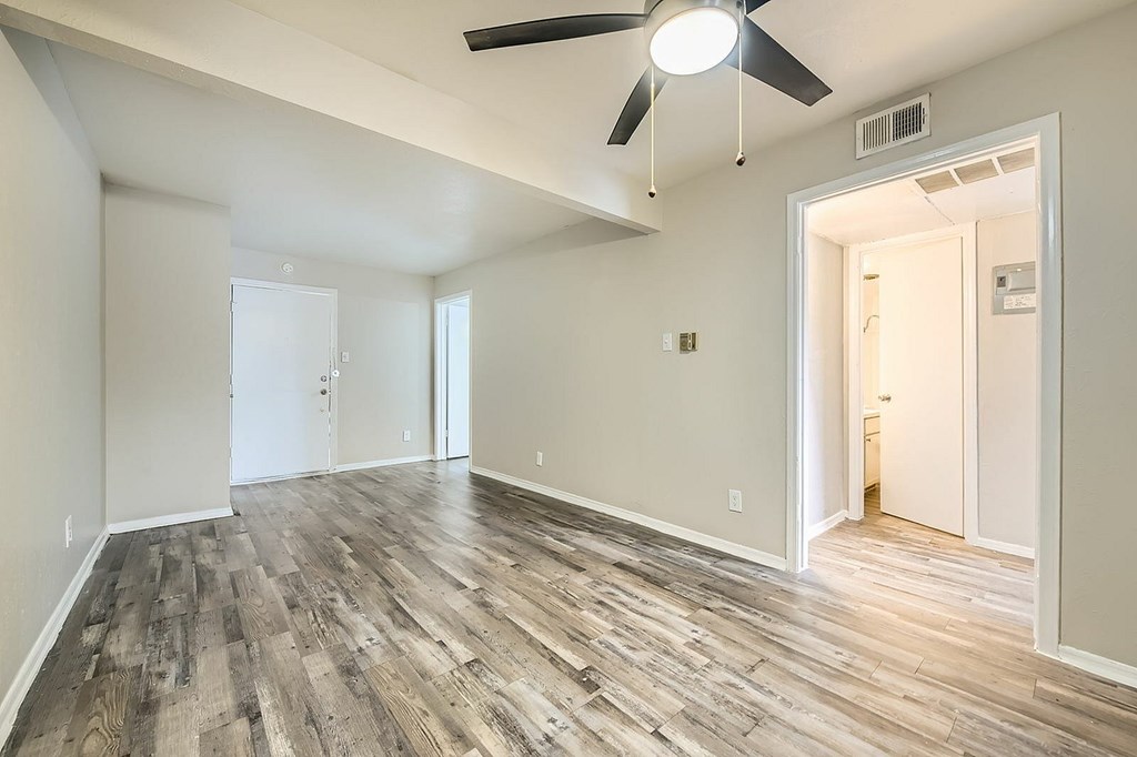 A room with a ceiling fan and wooden flooring.