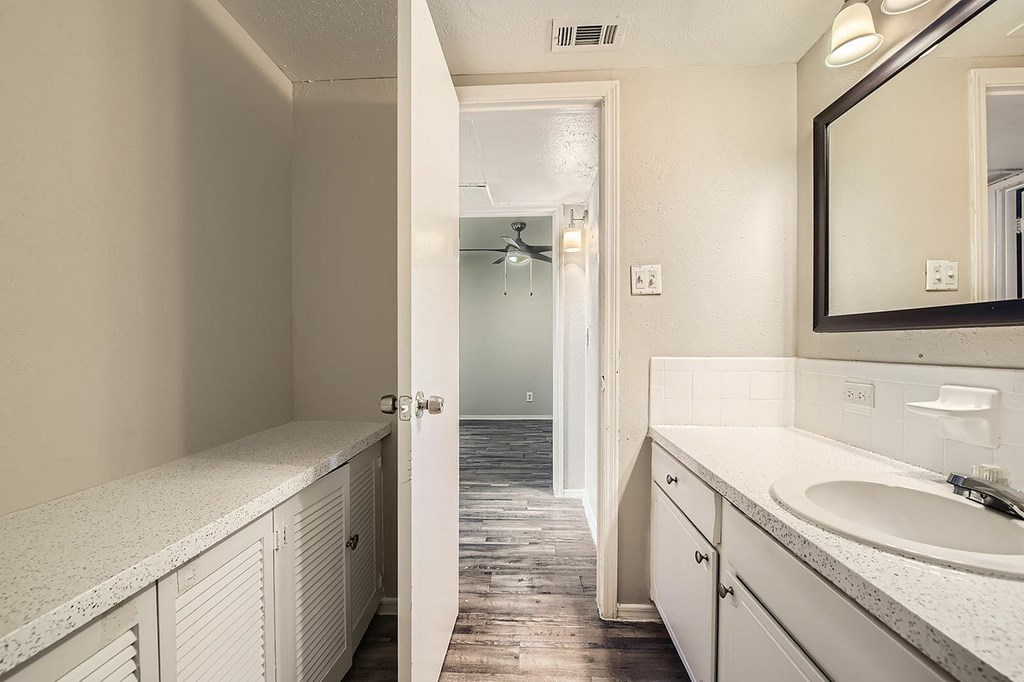 A bathroom with a white counter top and a white sink.