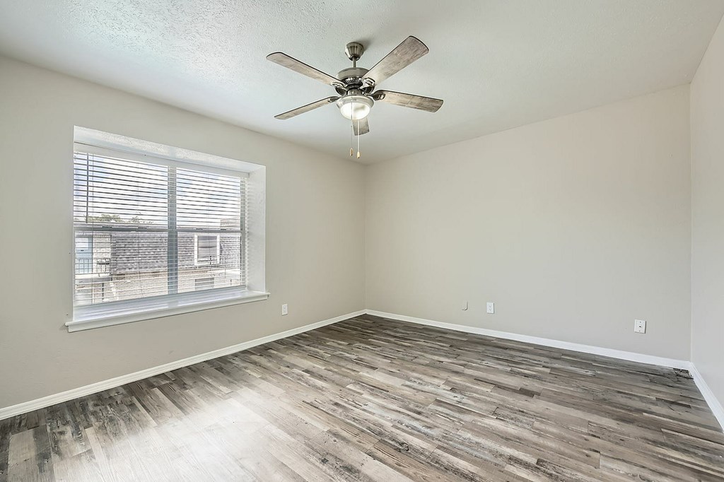 A room with a ceiling fan and a window with blinds.