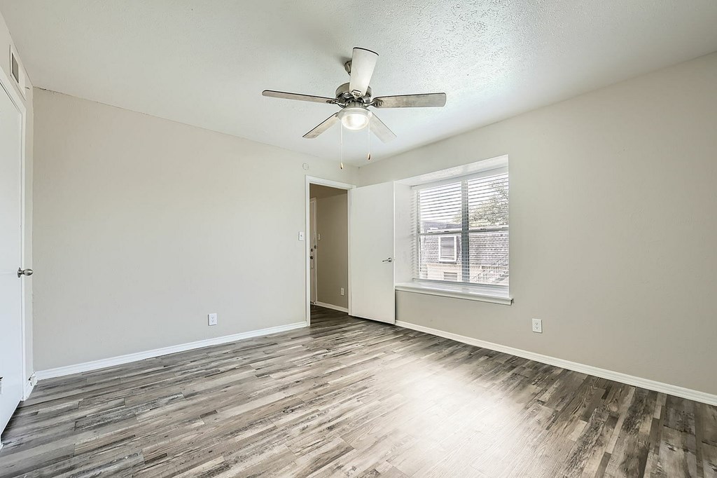 A room with a ceiling fan and wooden flooring.