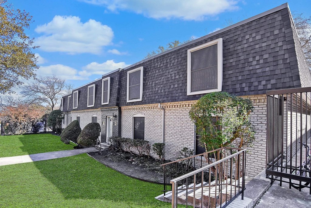 A house with a grey roof and a green lawn in front.