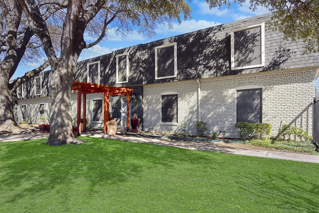 A house with a red pergola and a tree in front.