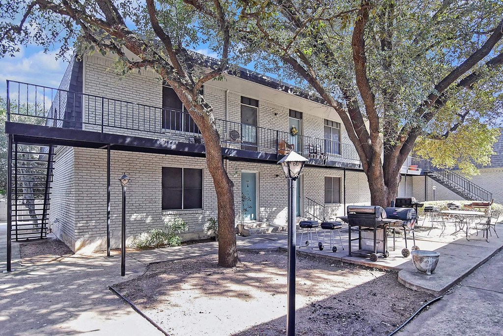 A tree in front of a building with a balcony.