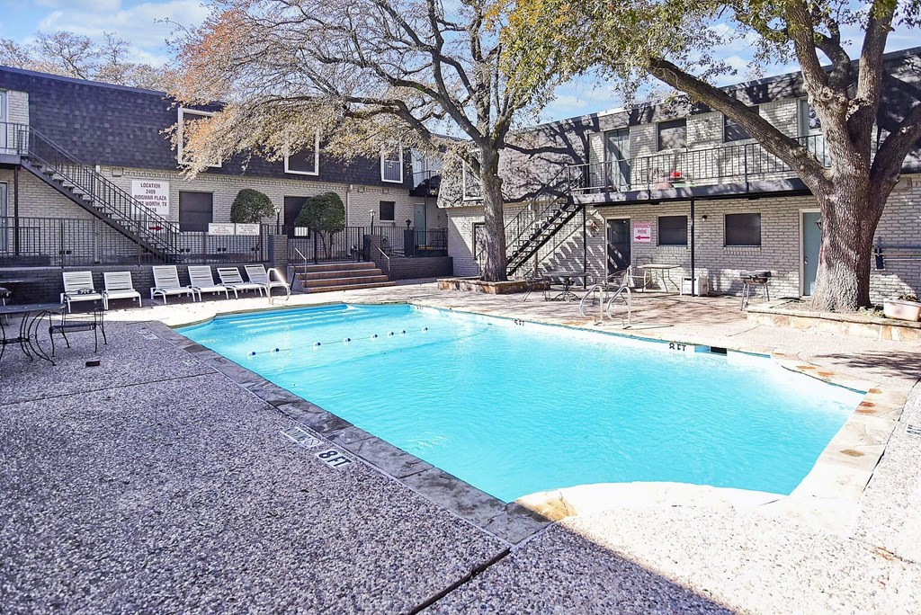 A small pool surrounded by a concrete floor and a building in the background.