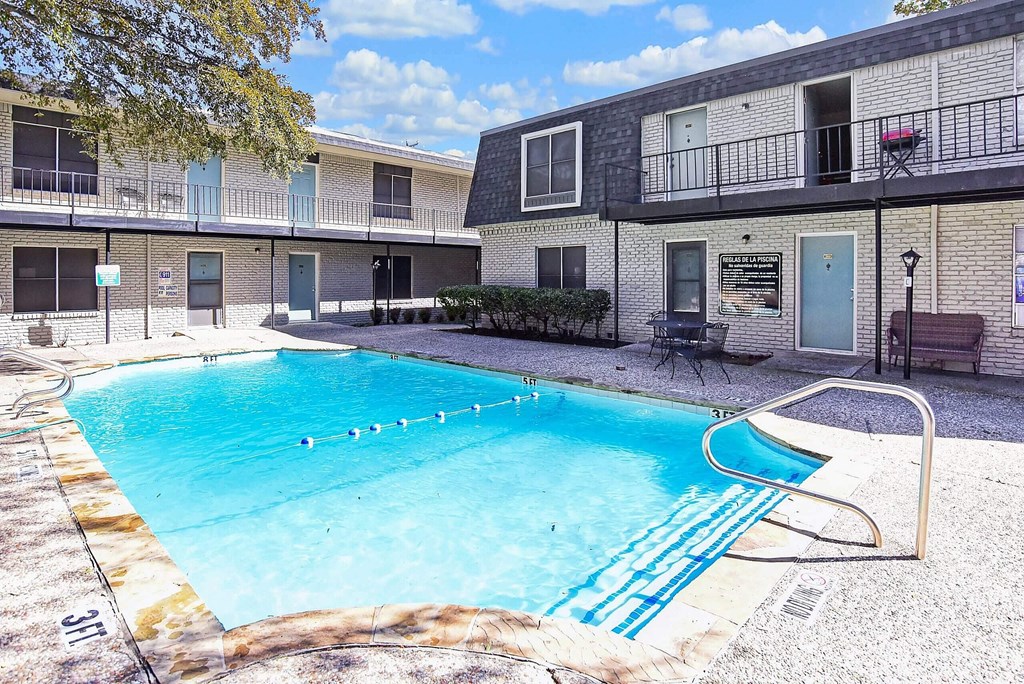 A swimming pool in front of a building with a blue sky in the background.