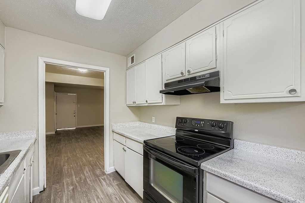 A kitchen with a black stove top oven and white cabinets.
