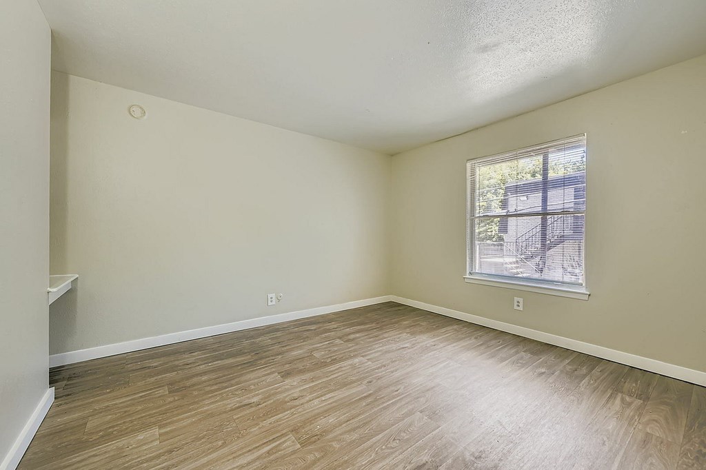 Empty room with a window and wooden flooring.