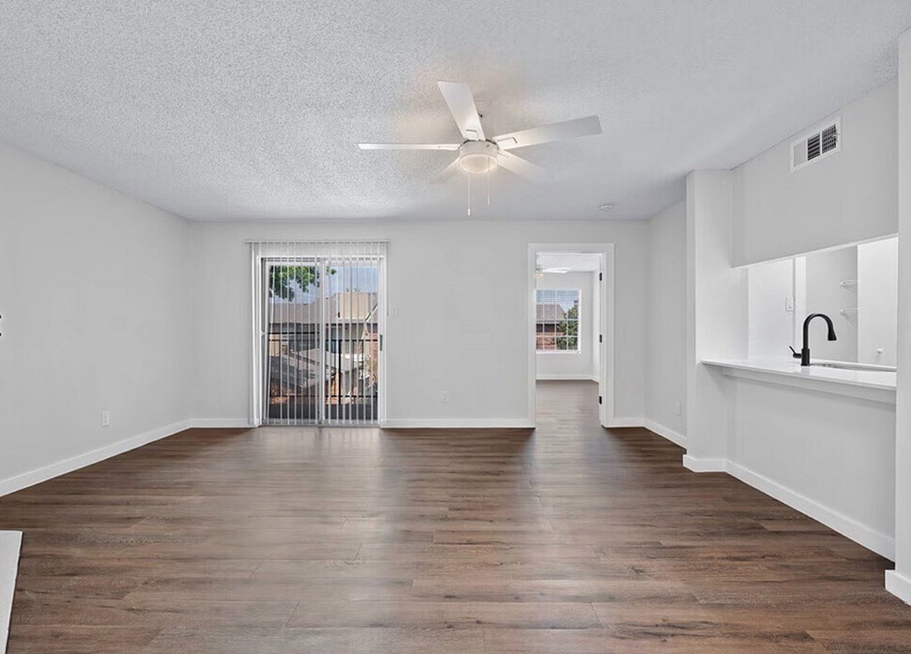 A spacious room with a ceiling fan and wooden flooring.
