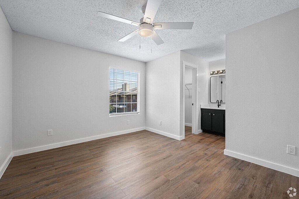 A room with a ceiling fan and wooden flooring.