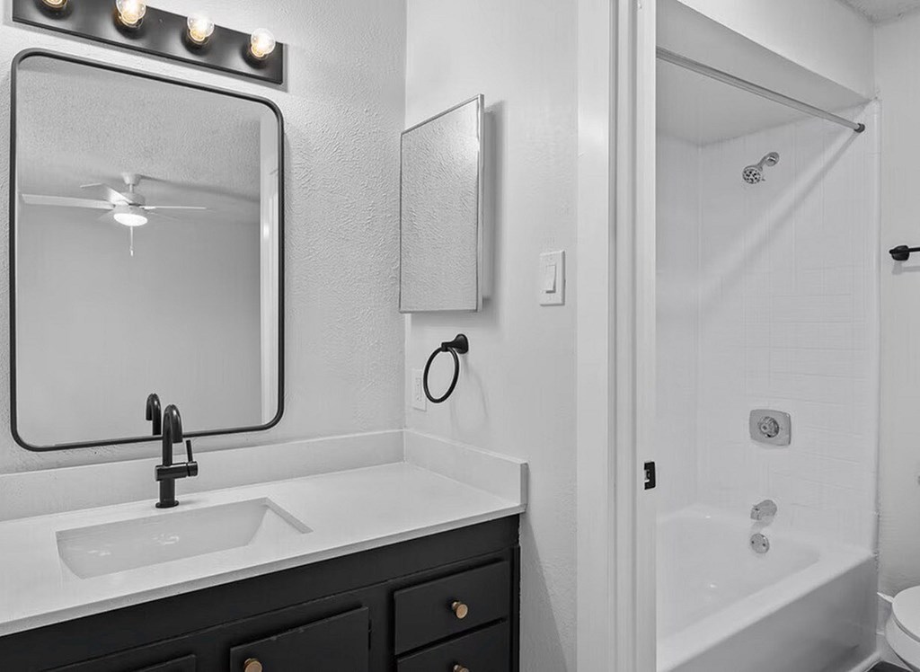 A bathroom with a sink, mirror, and shower.