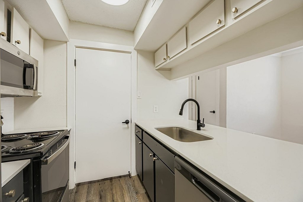 A kitchen with a white counter top and black appliances.