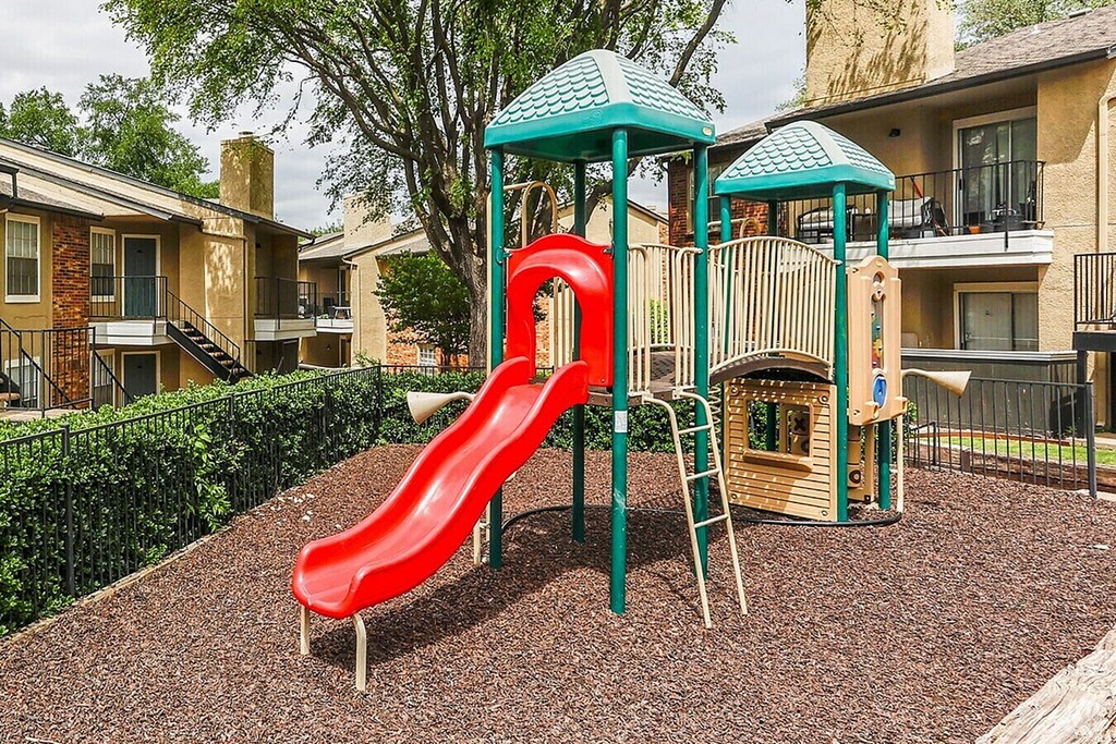 A red slide is the main feature of a playground in a residential area.