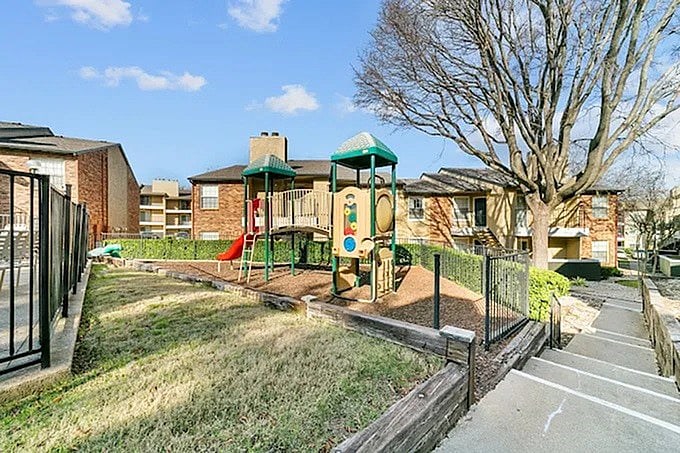 A playground with a green slide and a red swing set.