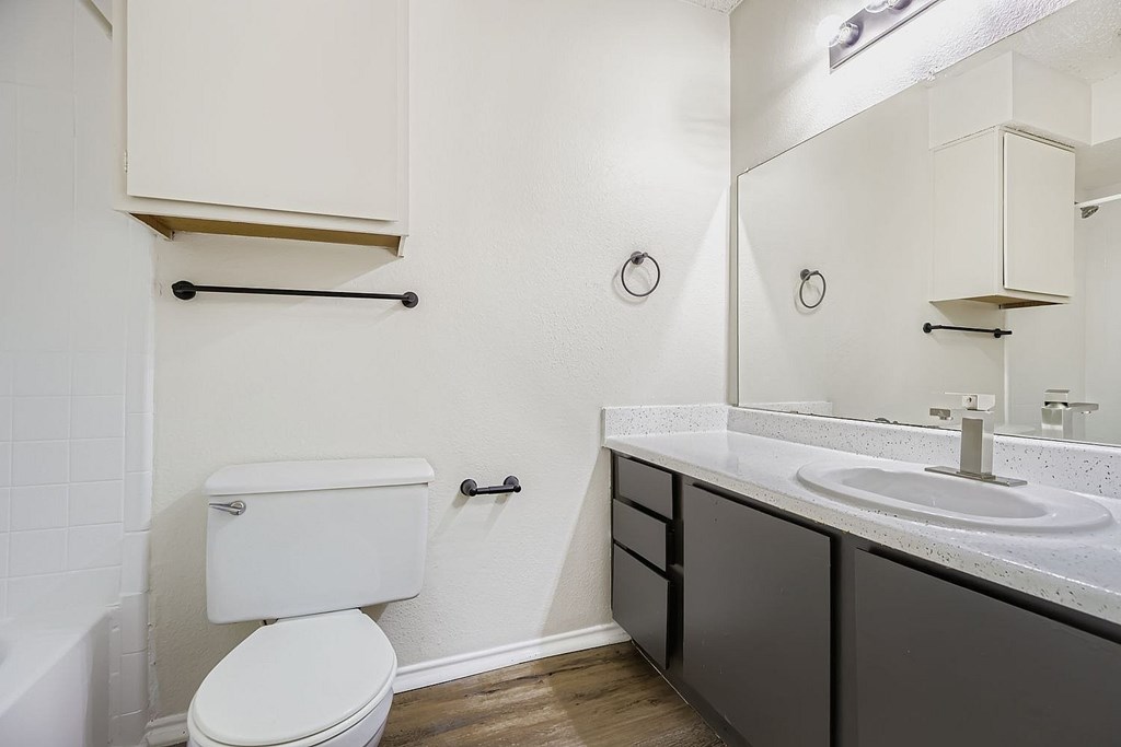A playground with a green and yellow structure, a red slide, and a black fence.