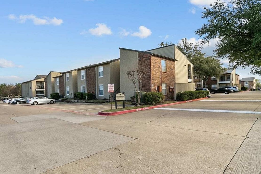 A parking lot in front of a building with a sign.