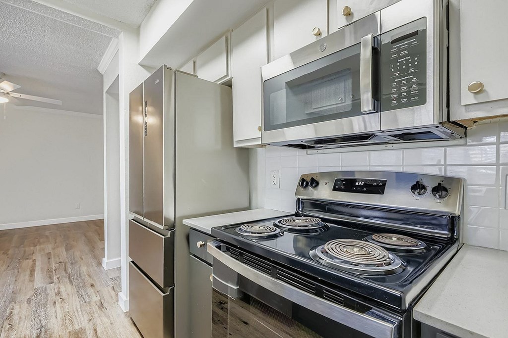 A modern kitchen with a stainless steel refrigerator, microwave, and oven.