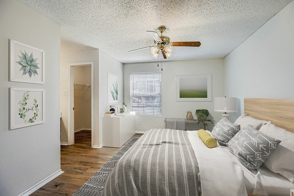 A small house with a gravel driveway in front of a multi-story apartment building.