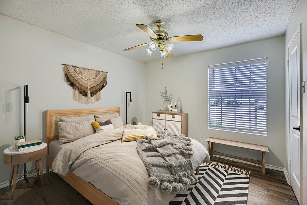 A bedroom with a bed, a ceiling fan, and a window with blinds.
