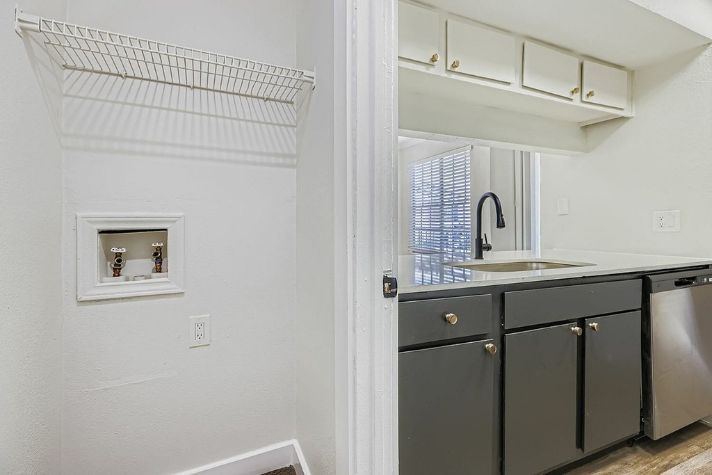 A kitchen with a white wall and a white sink.