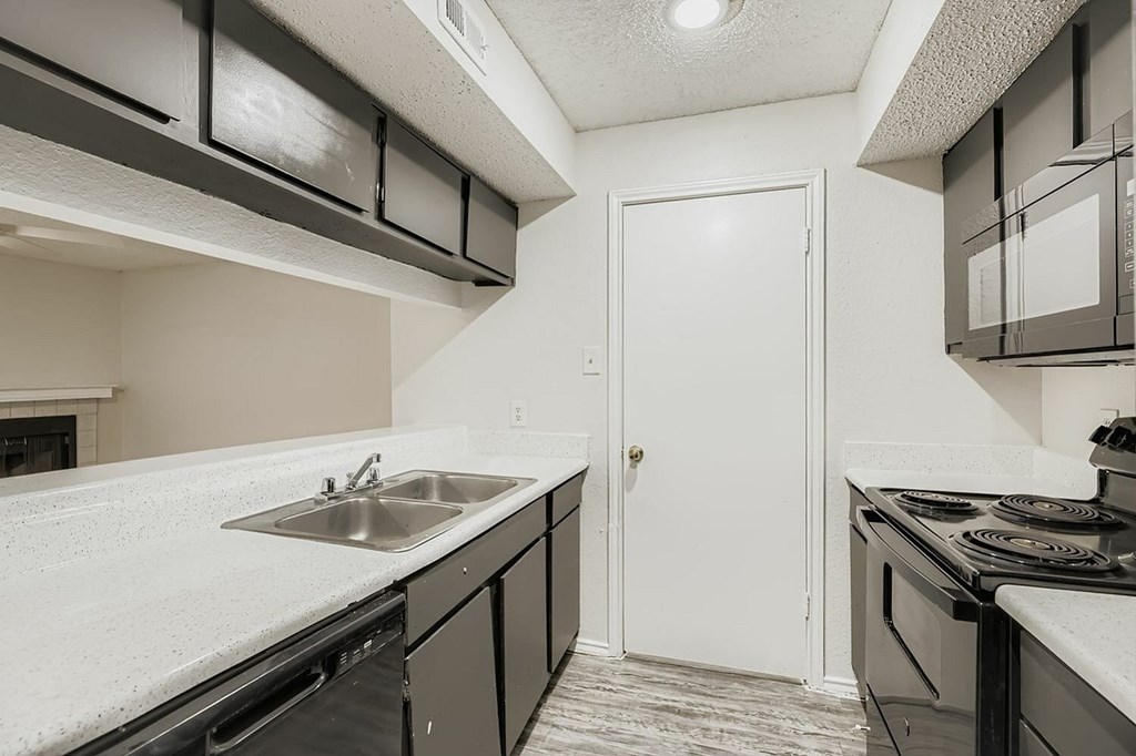 A kitchen with black cabinets and a white door.