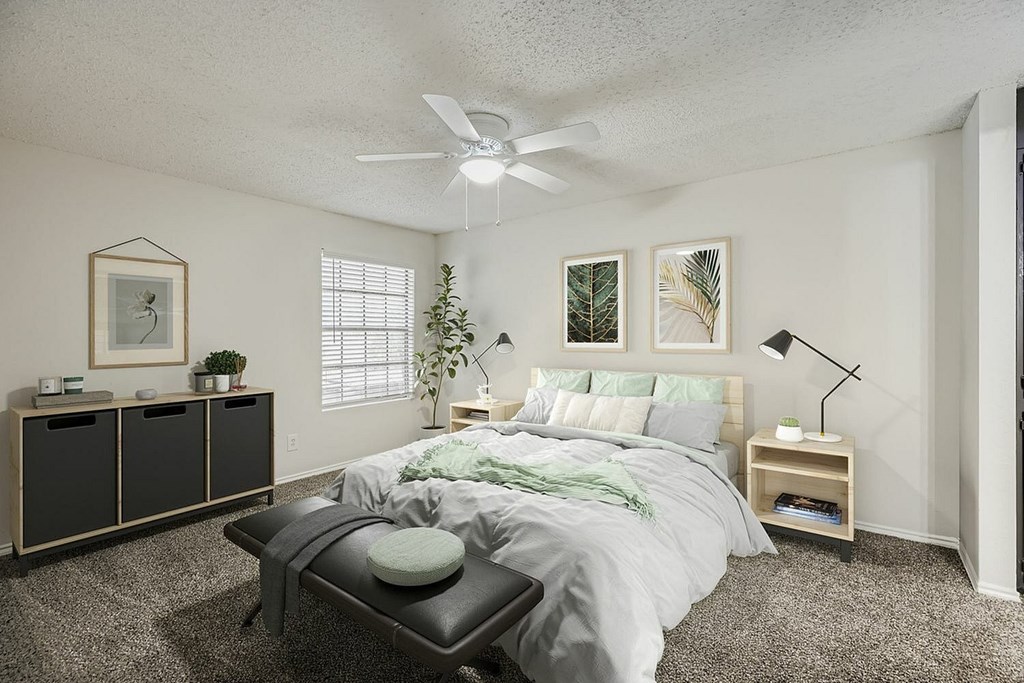 A bedroom with a bed, a bench, and a ceiling fan.