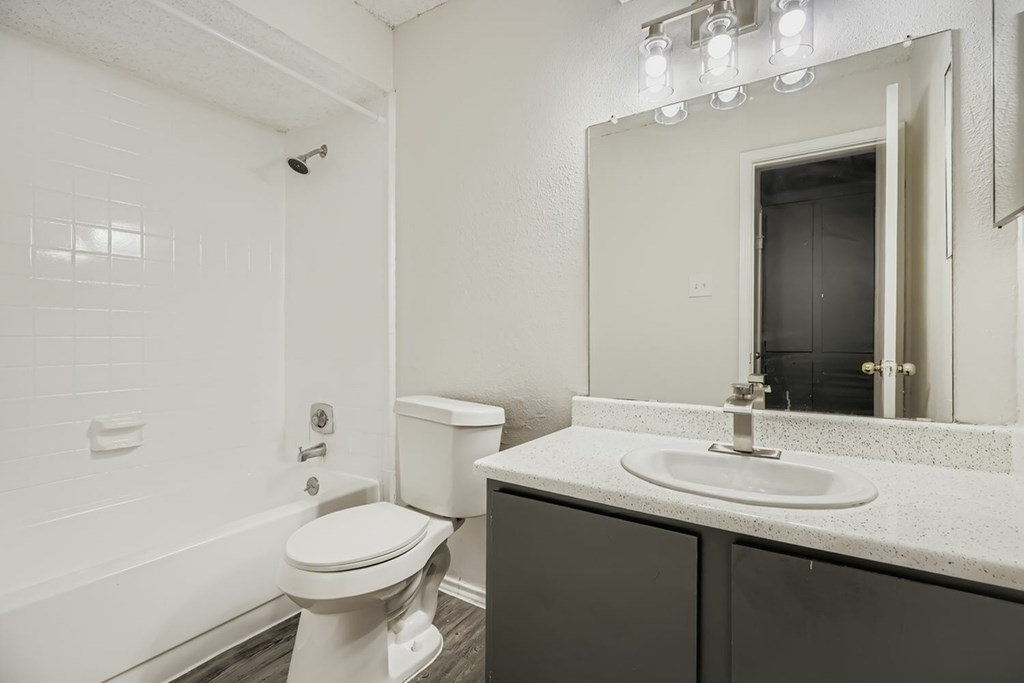 A white toilet sits in a bathroom next to a sink and a mirror.