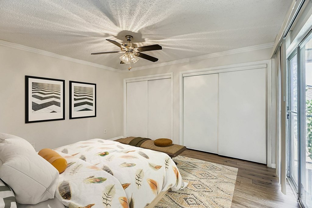 A bedroom with a bed, nightstand, and window with blinds.