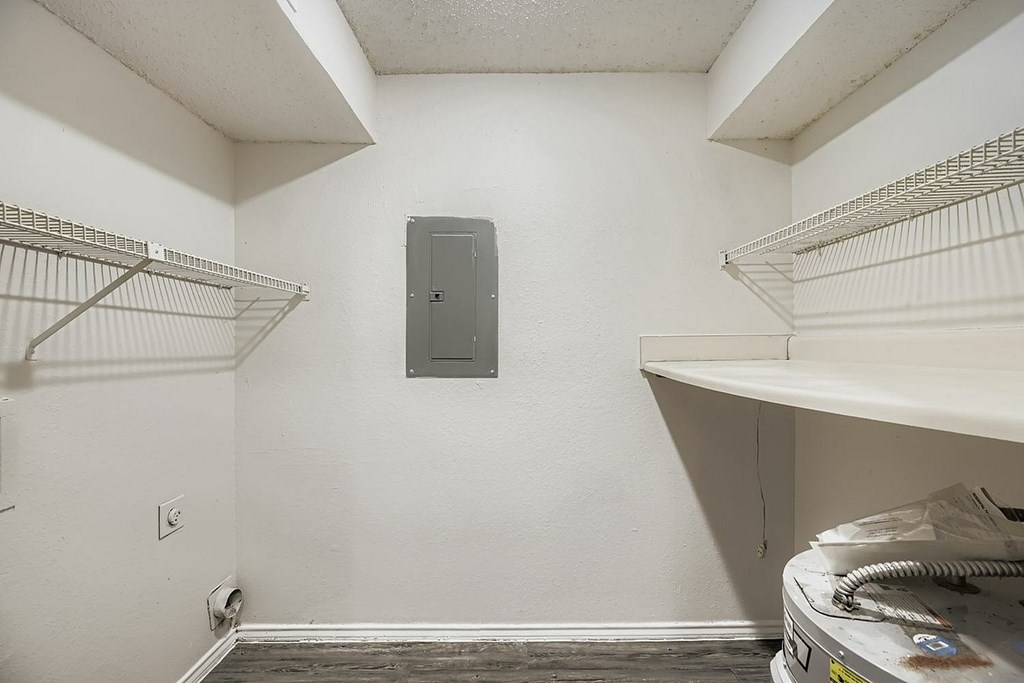 A room with a white wall and a metal shelf.