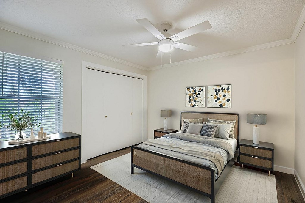 A bedroom with a bed, nightstands, and a ceiling fan.