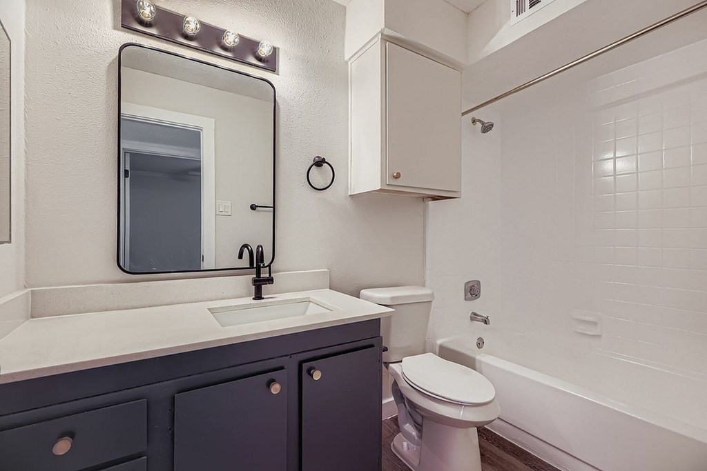 A white bathroom with a sink, toilet, and mirror.