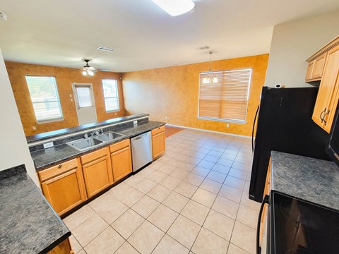 A kitchen with wooden cabinets and a black refrigerator.