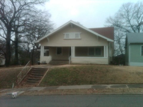A house with a white front porch and a brown roof.
