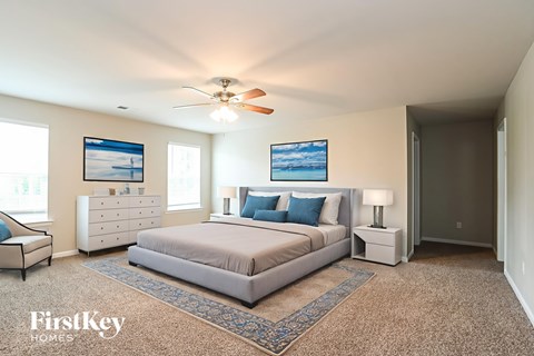 A bedroom with a bed, dresser, and ceiling fan.