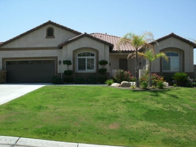 A house with a brown roof and a green lawn in front.