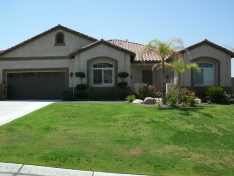 A house with a brown roof and a green lawn in front.