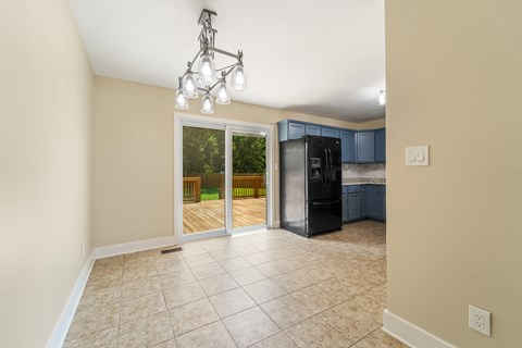 A kitchen area with a black refrigerator and a sliding glass door leading to a backyard.