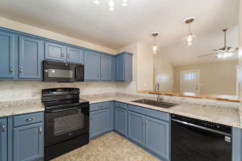 A kitchen with blue cabinets and black appliances.