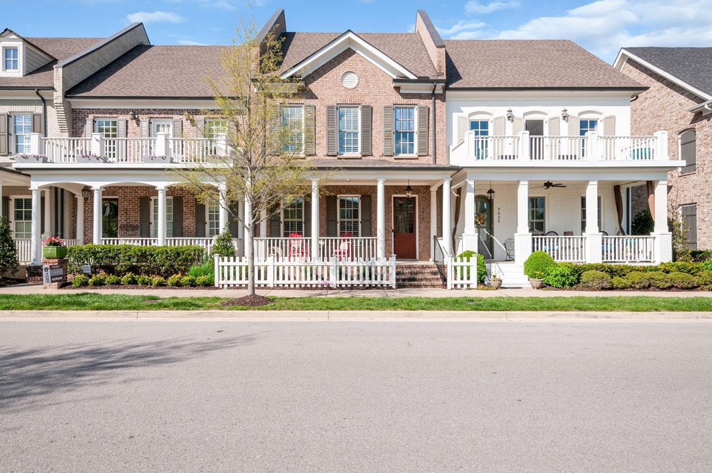 A large house with a white porch and a red door.