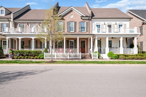 A large house with a white porch and a red door.