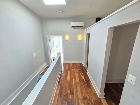 A long hallway with wood floors and white walls.
