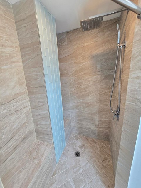 A shower with a tiled floor and a glass door.